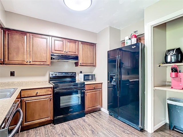 1520 NE 17th Ave, Ocala, FL 34470 - kitchen with black appliances, ventilation hood, light wood-style flooring, light countertops, and brown cabinets