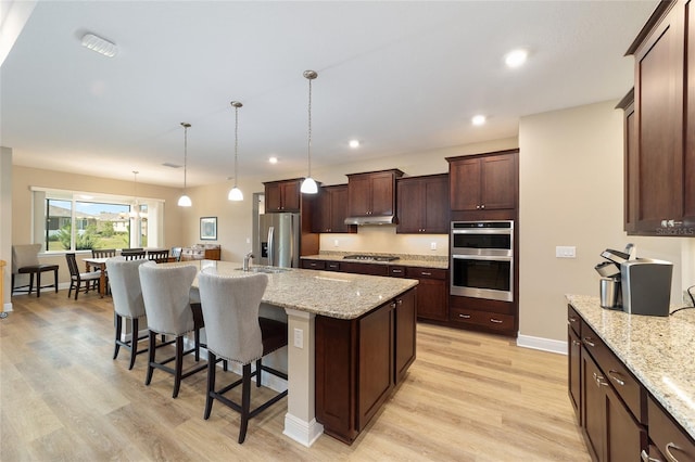 9607 SW 79th Lane Rd, Ocala, FL 34481 - kitchen featuring stainless steel appliances, light wood finished floors, a kitchen bar, a kitchen island with sink, and a sink