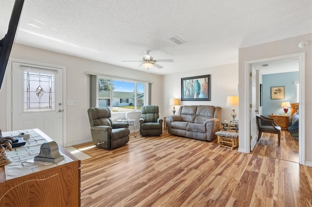 17890 SE 96th Ct, Summerfield, FL 34491 - living room with light wood-style flooring, ceiling fan, a textured ceiling, and baseboards