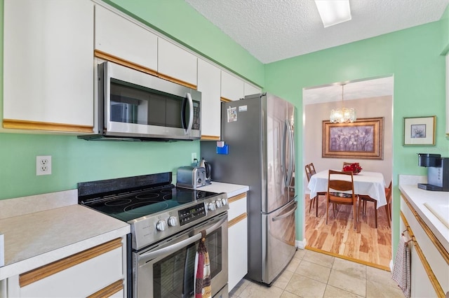 17890 SE 96th Ct, Summerfield, FL 34491 - kitchen featuring appliances with stainless steel finishes, light countertops, a chandelier, white cabinetry, and a textured ceiling