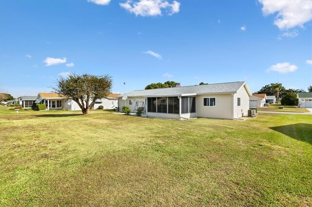 17890 SE 96th Ct, Summerfield, FL 34491 - rear view of house with a sunroom, central AC, and a lawn