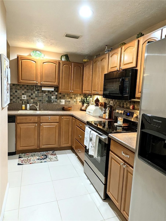 231 NE 28th Ave Unit 207, Ocala, FL 34470 - kitchen with stainless steel appliances, decorative backsplash, a textured ceiling, light tile patterned floors, and a sink