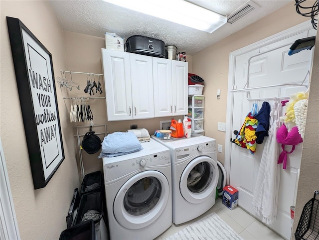 231 NE 28th Ave Unit 207, Ocala, FL 34470 - laundry area featuring washing machine and dryer, cabinet space, tile patterned floors, and a textured ceiling