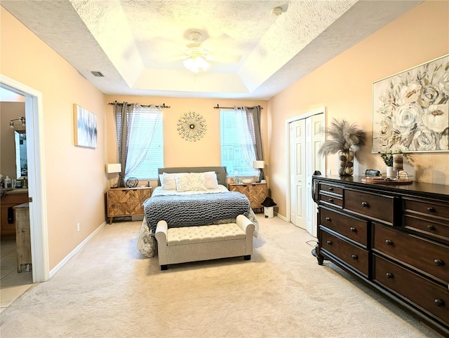 231 NE 28th Ave Unit 207, Ocala, FL 34470 - bedroom with a tray ceiling, a textured ceiling, light colored carpet, baseboards, and a ceiling fan