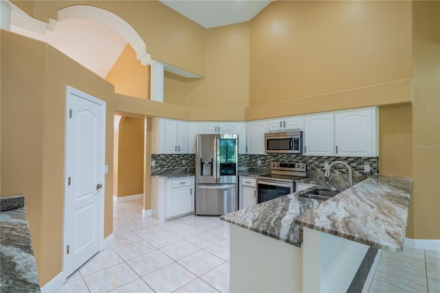 5815 NE 70th St, Silver Springs, FL 34488 - kitchen with appliances with stainless steel finishes, a sink, dark stone counters, a peninsula, and tasteful backsplash