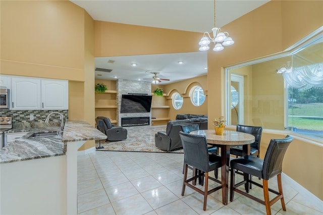 5815 NE 70th St, Silver Springs, FL 34488 - dining space featuring light tile patterned floors, high vaulted ceiling, a large fireplace, built in shelves, and a chandelier