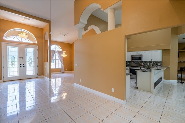 5815 NE 70th St, Silver Springs, FL 34488 - foyer featuring a towering ceiling, french doors, light tile patterned floors, a chandelier, and baseboards