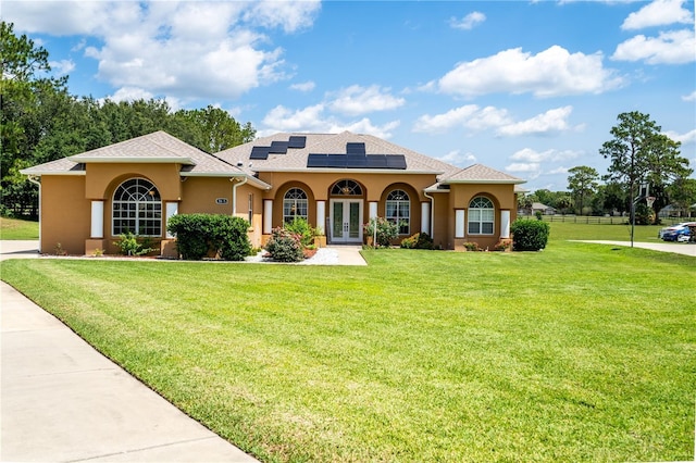 5815 NE 70th St, Silver Springs, FL 34488 - mediterranean / spanish house with french doors, stucco siding, a front lawn, roof mounted solar panels, and a shingled roof