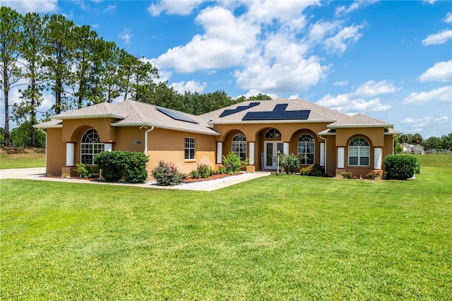 5815 NE 70th St, Silver Springs, FL 34488 - mediterranean / spanish-style home with stucco siding, a front lawn, solar panels, and french doors