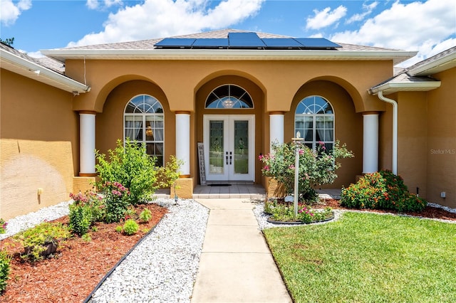 5815 NE 70th St, Silver Springs, FL 34488 - property entrance featuring french doors, stucco siding, roof mounted solar panels, and a yard