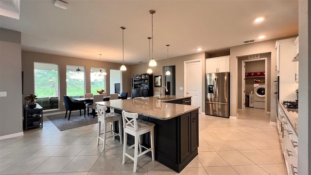 10287 SW 96th Ln, Ocala, FL 34481 - kitchen with stainless steel appliances, washer / dryer, light tile patterned flooring, light stone counters, and white cabinets