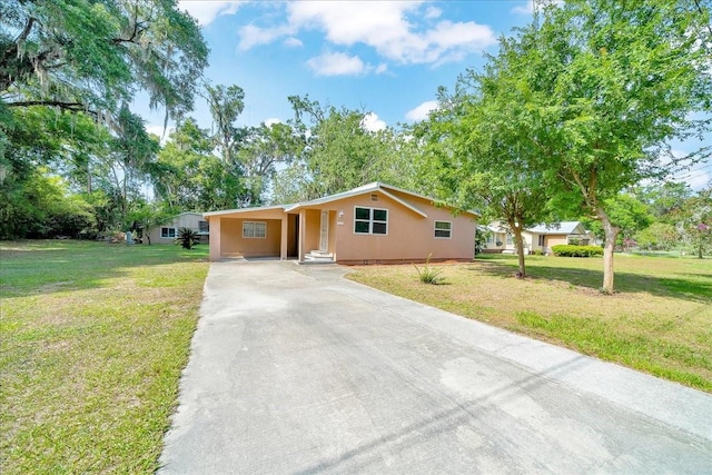 1322 NE 53rd St, Ocala, FL 34479 - ranch-style house with concrete driveway, a front lawn, a carport, and view of scattered trees