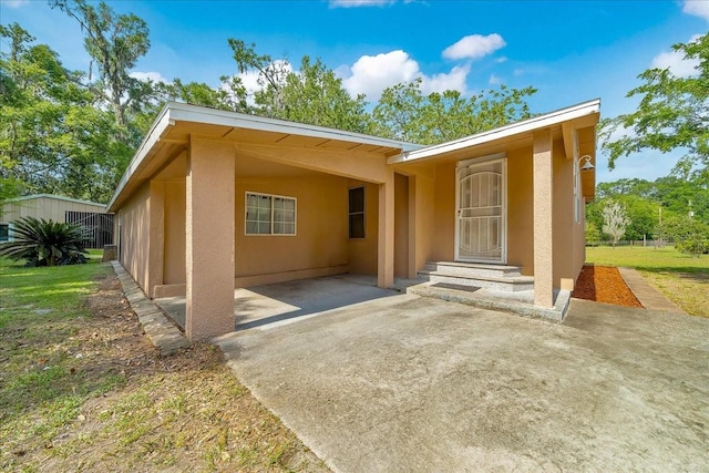 1322 NE 53rd St, Ocala, FL 34479 - view of exterior entry featuring stucco siding, driveway, and an attached carport