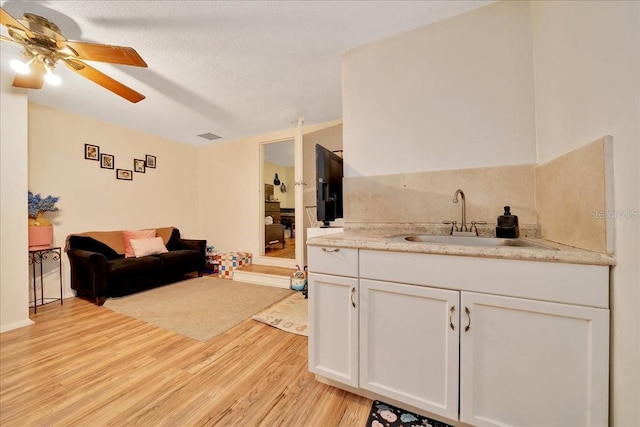 1322 NE 53rd St, Ocala, FL 34479 - kitchen with white cabinetry, light wood finished floors, open floor plan, ceiling fan, and a sink