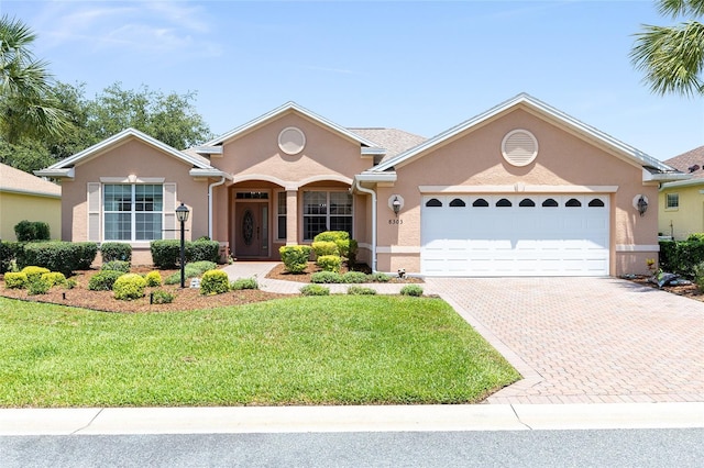 8303 SW 82nd Cir, Ocala, FL 34481 - view of front of house with stucco siding, a garage, decorative driveway, and a front lawn