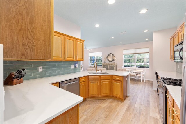 8303 SW 82nd Cir, Ocala, FL 34481 - kitchen with appliances with stainless steel finishes, a sink, a peninsula, light wood-type flooring, and decorative backsplash