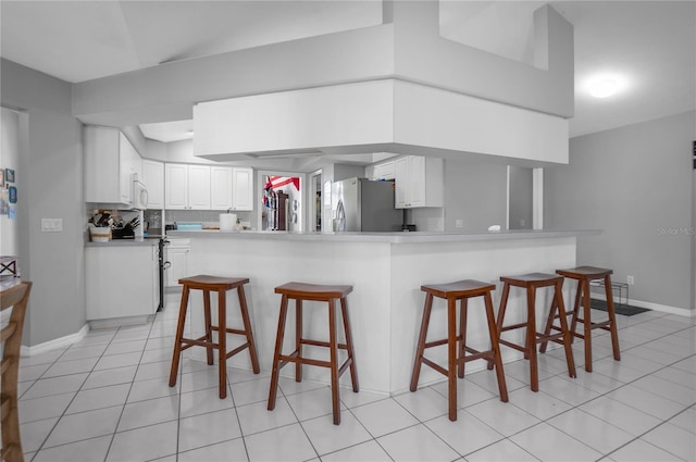 8015 N Tower Way, Citrus Springs, FL 34434 - kitchen featuring stainless steel fridge, a kitchen bar, white cabinets, a peninsula, and baseboards