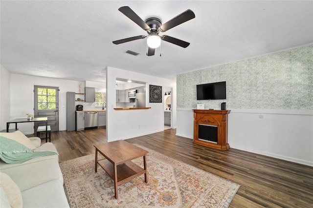 4601 SE 18th Ave, Ocala, FL 34480 - living area featuring ceiling fan, dark wood finished floors, wallpapered walls, a textured ceiling, and baseboards