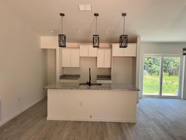 5701 NW 6th Pl, Ocala, FL 34482 - kitchen featuring an island with sink, white cabinets, wood finished floors, recessed lighting, and stone counters