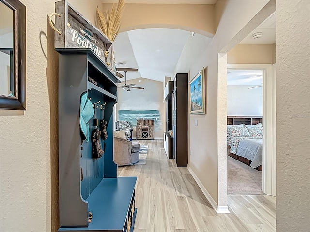 6812 Gideon Cir, Zephyrhills, FL 33541 - hall featuring a textured wall, arched walkways, wood finished floors, vaulted ceiling, and baseboards