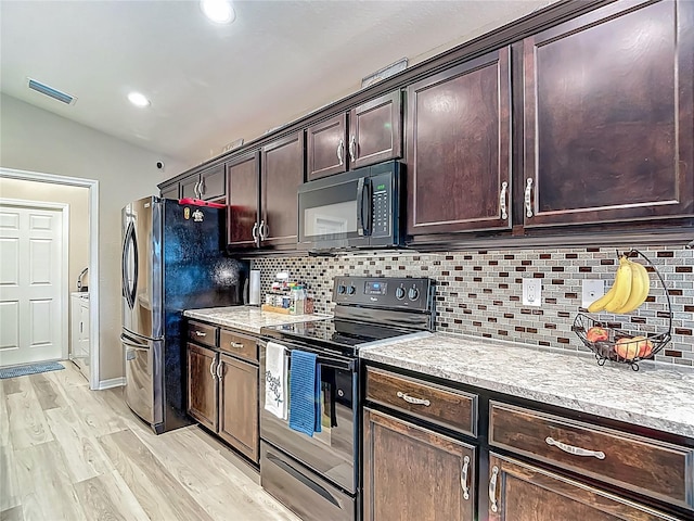 6812 Gideon Cir, Zephyrhills, FL 33541 - kitchen featuring black appliances, decorative backsplash, light wood-type flooring, dark brown cabinets, and vaulted ceiling