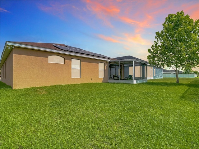 6812 Gideon Cir, Zephyrhills, FL 33541 - rear view of house with a sunroom, solar panels, stucco siding, and a lawn