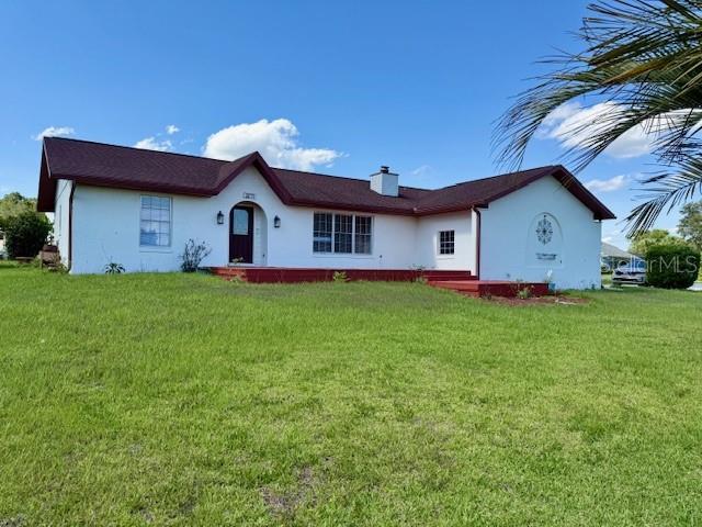 8770 SW 196th Terrace Rd, Dunnellon, FL 34432 - back of property with stucco siding, a yard, and a chimney