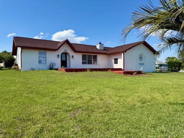 8770 SW 196th Terrace Rd, Dunnellon, FL 34432 - view of front facade with a front lawn, stucco siding, and a chimney