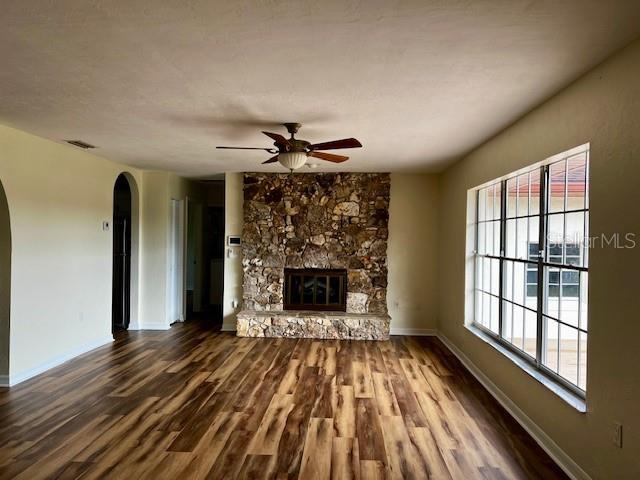 8770 SW 196th Terrace Rd, Dunnellon, FL 34432 - unfurnished living room featuring arched walkways, wood finished floors, baseboards, and ceiling fan