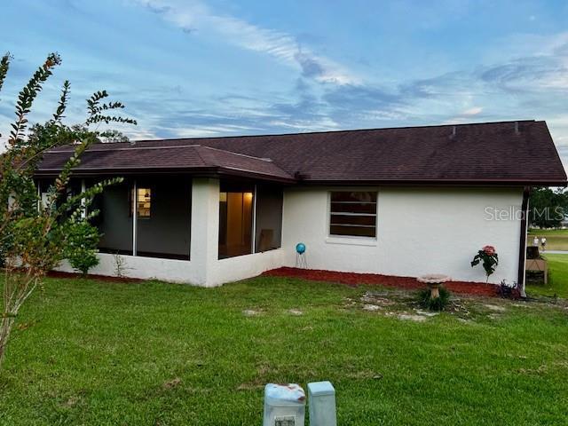 8770 SW 196th Terrace Rd, Dunnellon, FL 34432 - rear view of house with a yard, a sunroom, stucco siding, and roof with shingles