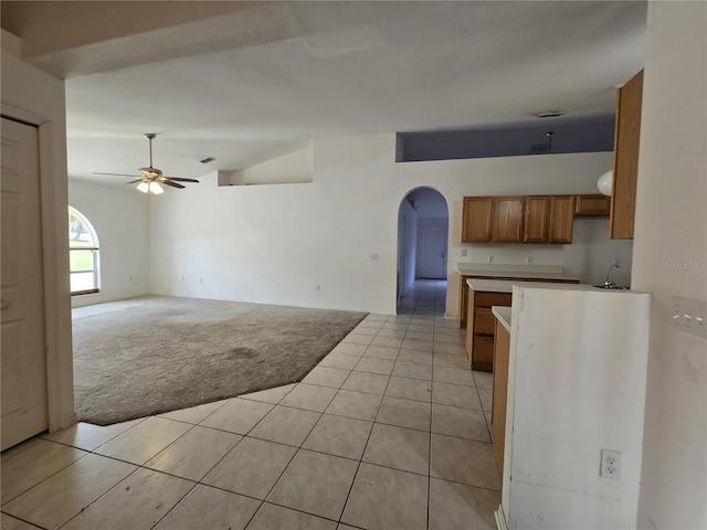 4460 SW 44th St, Ocala, FL 34474 - kitchen with ceiling fan, arched walkways, brown cabinets, vaulted ceiling, and light carpet