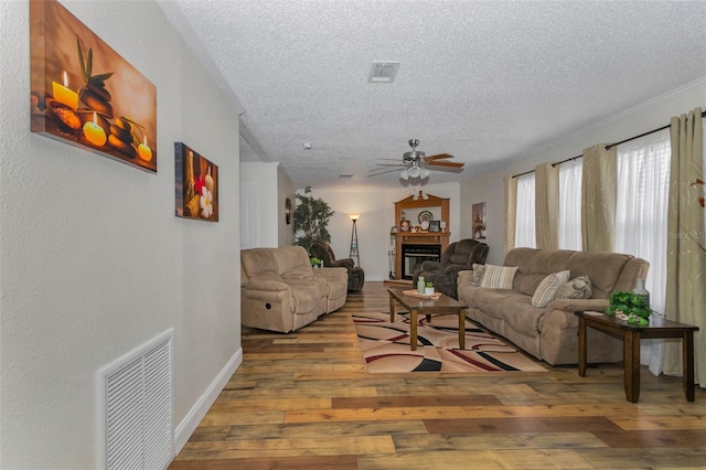14276 SE 61st Ave, Summerfield, FL 34491 - living room with a textured ceiling, a ceiling fan, wood finished floors, a glass covered fireplace, and baseboards