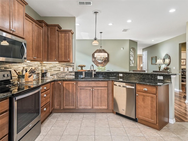 8447 SW 82nd Loop, Ocala, FL 34481 - kitchen featuring appliances with stainless steel finishes, a sink, a peninsula, backsplash, and brown cabinets