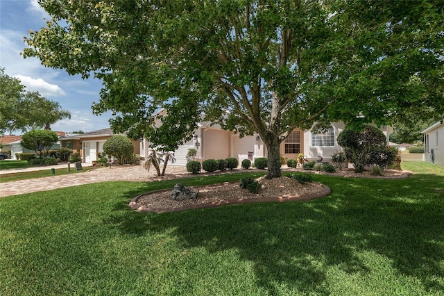 1748 SW 157th Place Rd, Ocala, FL 34473 - obstructed view of property with curved driveway, a front yard, stucco siding, and a garage