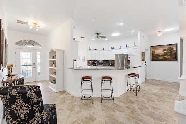 3141 Roswell Rd, The Villages, FL 32162 - kitchen with freestanding refrigerator, a breakfast bar, a peninsula, a ceiling fan, and white cabinetry