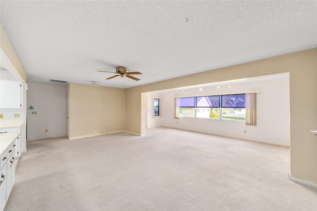 8885 SW 90th Ave, Ocala, FL 34481 - unfurnished living room with a ceiling fan, a textured ceiling, light colored carpet, and baseboards
