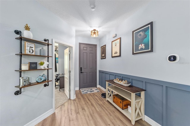 7479 SW 130th Ln, Ocala, FL 34473 - foyer entrance with light wood finished floors, a textured ceiling, and wainscoting
