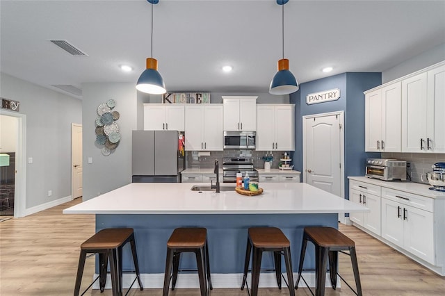 7479 SW 130th Ln, Ocala, FL 34473 - kitchen with appliances with stainless steel finishes, a sink, a kitchen breakfast bar, tasteful backsplash, and light wood-style flooring