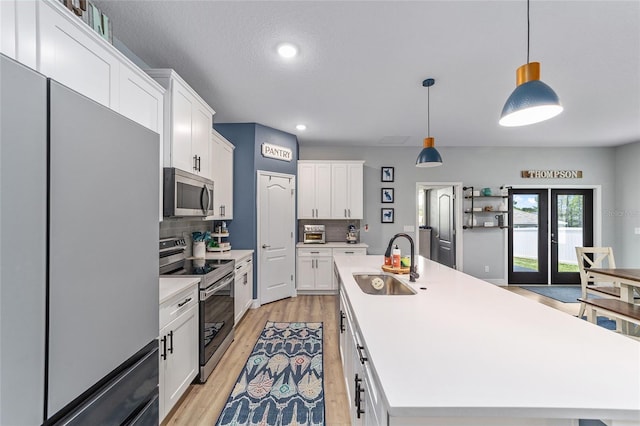 7479 SW 130th Ln, Ocala, FL 34473 - kitchen featuring stainless steel appliances, a sink, decorative backsplash, white cabinetry, and an island with sink