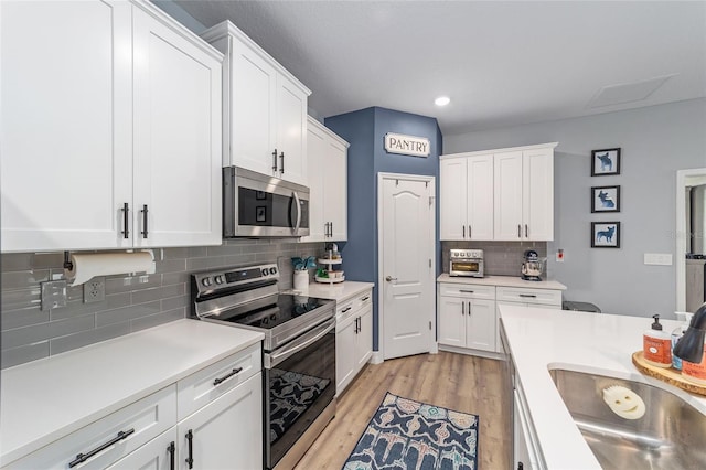 7479 SW 130th Ln, Ocala, FL 34473 - kitchen featuring appliances with stainless steel finishes, white cabinets, decorative backsplash, light countertops, and recessed lighting