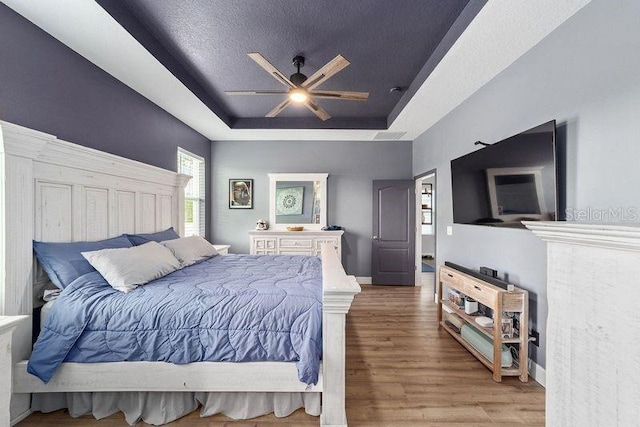 7479 SW 130th Ln, Ocala, FL 34473 - bedroom with a tray ceiling, wood finished floors, ceiling fan, a textured ceiling, and baseboards