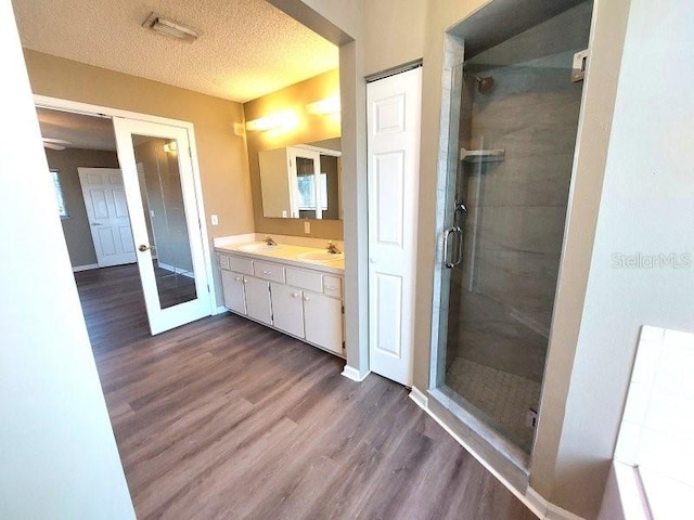 5110 NW 19th Pl, Ocala, FL 34482 - bathroom featuring wood finished floors, double vanity, a stall shower, french doors, and a textured ceiling