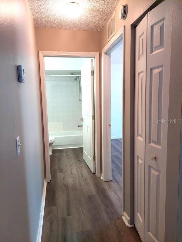 5110 NW 19th Pl, Ocala, FL 34482 - hall featuring dark wood-style floors, a textured ceiling, and baseboards