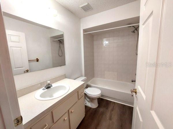 5110 NW 19th Pl, Ocala, FL 34482 - bathroom featuring toilet, vanity, wood finished floors, washtub / shower combination, and a textured ceiling