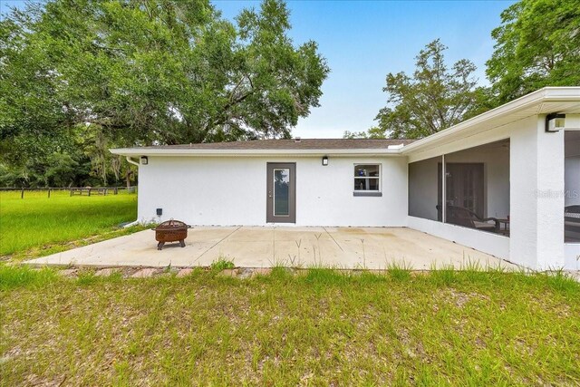 6350 NW 135th Ave, Morriston, FL 32668 - back of property with an outdoor fire pit, a patio, stucco siding, and a sunroom
