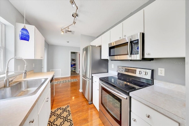 6350 NW 135th Ave, Morriston, FL 32668 - kitchen with appliances with stainless steel finishes, a sink, light wood-style flooring, white cabinets, and light countertops