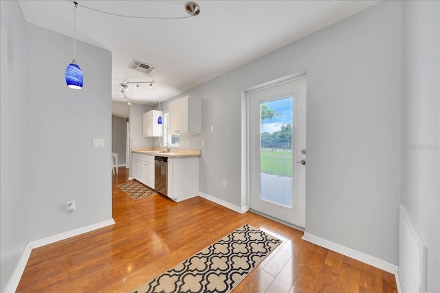 6350 NW 135th Ave, Morriston, FL 32668 - kitchen with stainless steel dishwasher, white cabinets, light wood-style flooring, light countertops, and baseboards