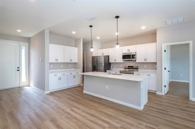 10207 SW 41st Ter W, Ocala, FL 34476 - kitchen with stainless steel appliances, light wood-style floors, light countertops, white cabinetry, and an island with sink