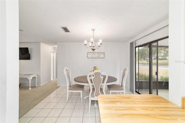 2701 NE 10th St Unit 101, Ocala, FL 34470 - dining room with a chandelier, a textured ceiling, light tile patterned flooring, light carpet, and baseboards