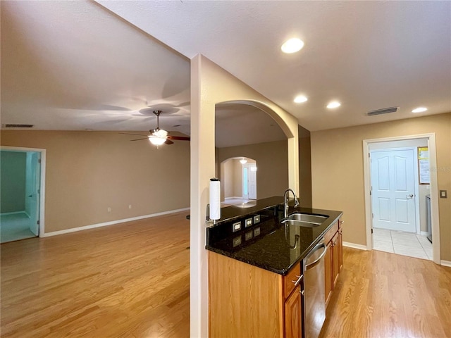 16405 SW 14th Avenue Rd, Ocala, FL 34473 - kitchen with a sink, stainless steel dishwasher, arched walkways, dark stone counters, and light wood finished floors